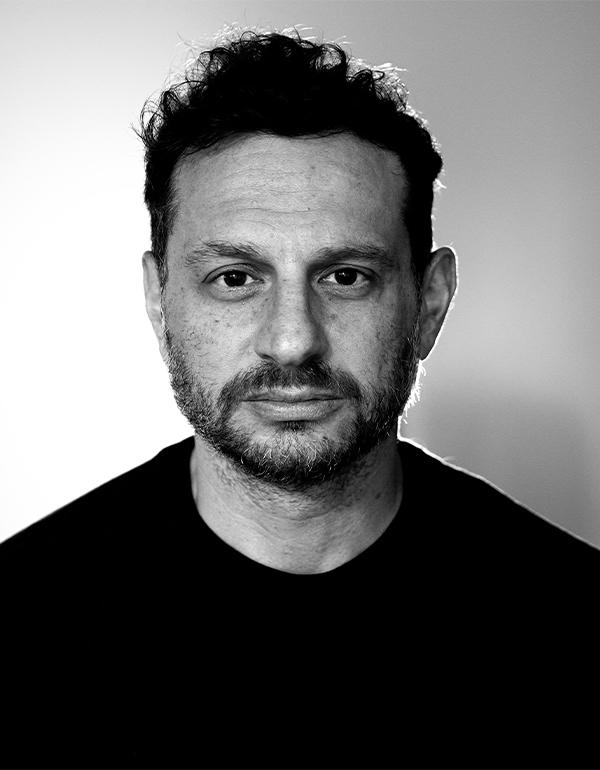 A front facing headshot in black and white of director Nick Psinakis.