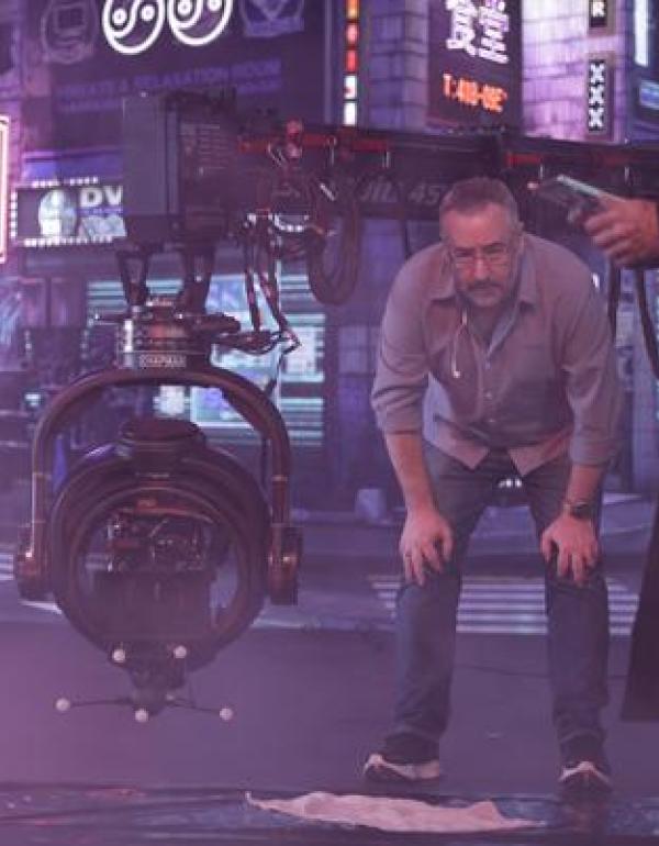 Director Jay Holben observes a setup beside a Technocrane and remote camera head on a smoky set