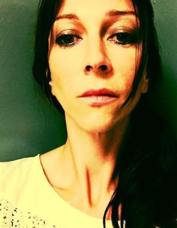 A woman with dark hair stares head on into the camera