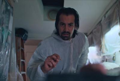 A man holding chopsticks approaches eye creature