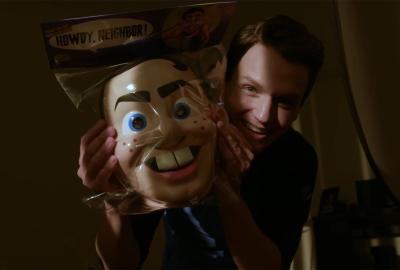 A man holds a creepy bucktooth mask in a bag