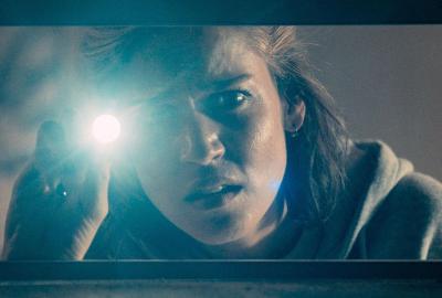 Serena uses a flash light to look through a window.