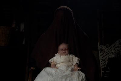 A deceased baby being held by the hidden mother
