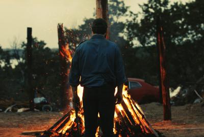 Man looks at a bonfire