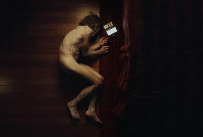 A naked man in the fetal position