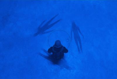 A man looks down at three shadowy figures