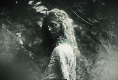 The terrifying silhouette of a woman with long curly hair and glowing eyes, in a black and white image.
