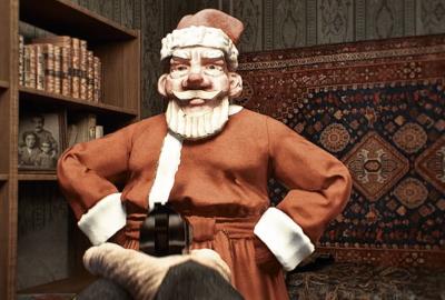 Santa Claus looks at the person pointing a gun at him.