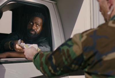 A man in a truck is stopped showing paper at a checkpoint