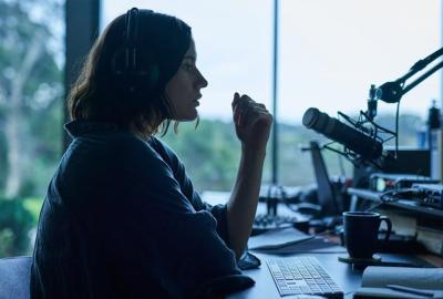 woman podcaster speaks into microphone