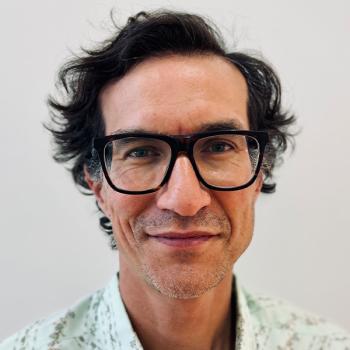 A front facing headshot in glasses of director Kevin Ignatius.