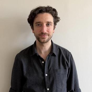 Picture of Anthony Tueni : 1m85, curly chestnut hair, and a light beard.